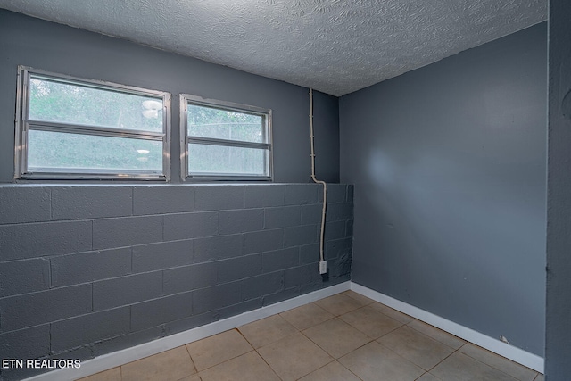 unfurnished room with tile patterned flooring, a textured ceiling, and a healthy amount of sunlight