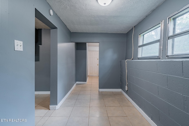 corridor with a textured ceiling and light tile patterned flooring