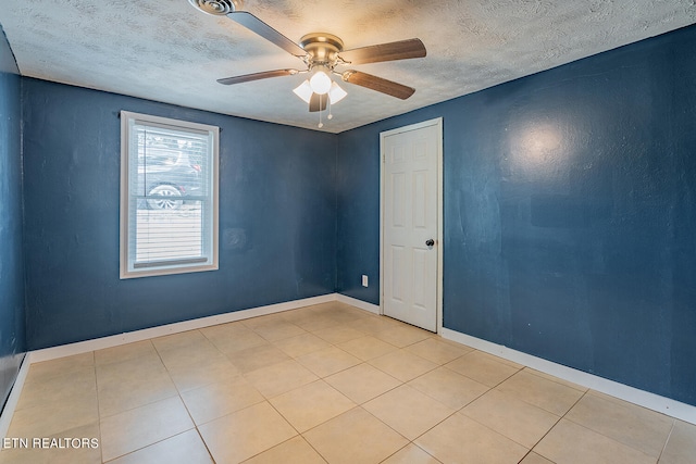 tiled empty room with ceiling fan and a textured ceiling