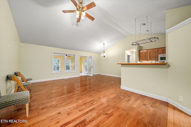 living room with light hardwood / wood-style flooring, ceiling fan, sink, and vaulted ceiling