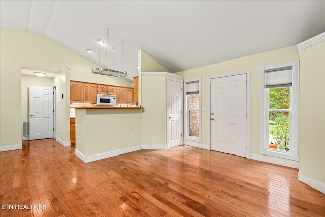 interior space with kitchen peninsula, light hardwood / wood-style flooring, vaulted ceiling, and a breakfast bar