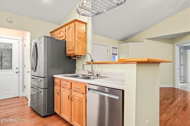 kitchen featuring sink, light wood-type flooring, appliances with stainless steel finishes, and vaulted ceiling