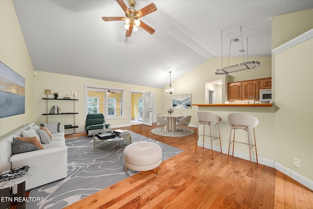 living room with ceiling fan, sink, light hardwood / wood-style flooring, and vaulted ceiling