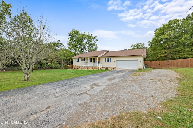 ranch-style house featuring a front lawn, covered porch, and a garage