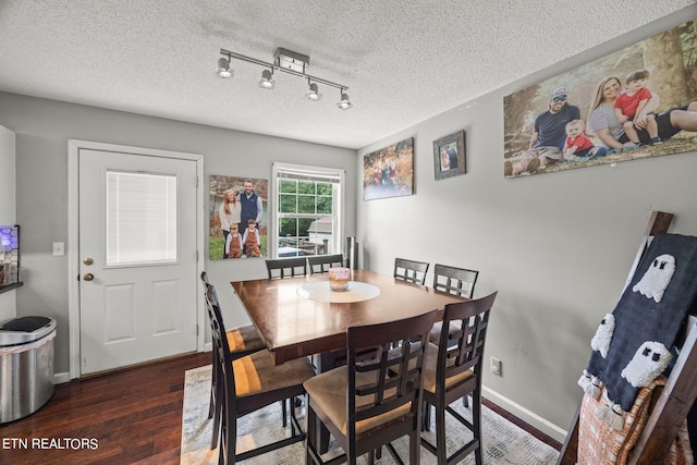 dining space featuring a textured ceiling, dark hardwood / wood-style floors, and track lighting