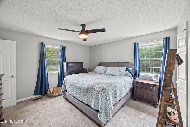 bedroom featuring ceiling fan, light colored carpet, and a textured ceiling