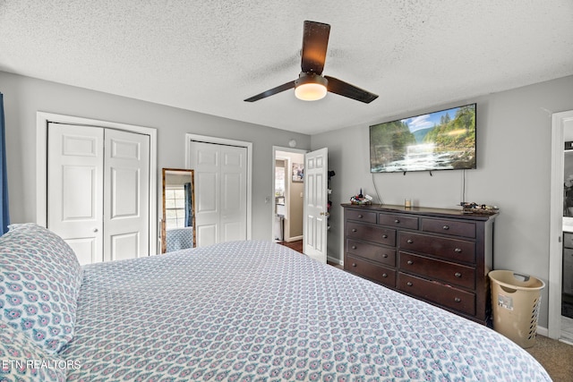 bedroom with two closets, ceiling fan, carpet flooring, and a textured ceiling