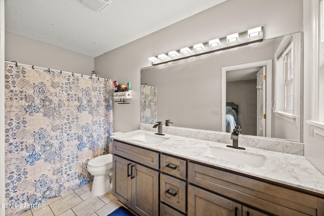 bathroom with a textured ceiling, walk in shower, tile patterned floors, vanity, and toilet