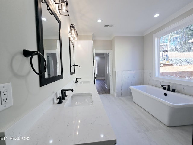 bathroom featuring a sink, visible vents, a soaking tub, and crown molding