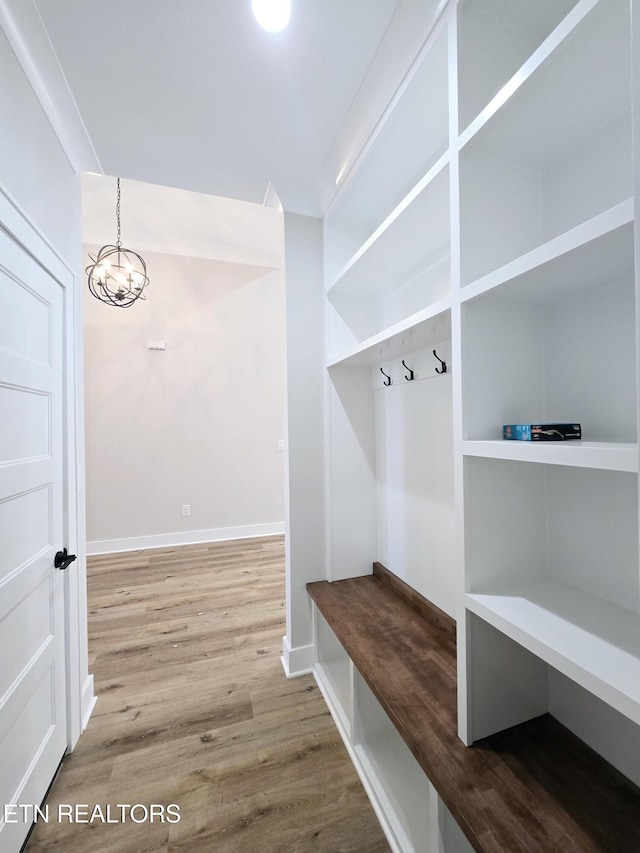 mudroom with an inviting chandelier, wood finished floors, and baseboards