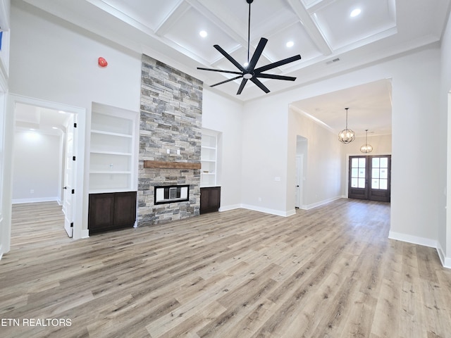 unfurnished living room featuring baseboards, coffered ceiling, a stone fireplace, and wood finished floors