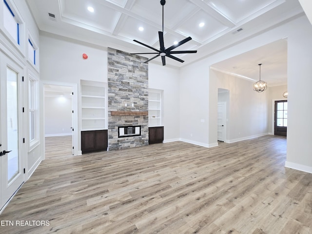 unfurnished living room featuring visible vents, a high ceiling, a stone fireplace, and wood finished floors