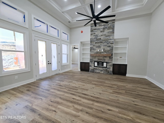 unfurnished living room with a stone fireplace, wood finished floors, a ceiling fan, and coffered ceiling