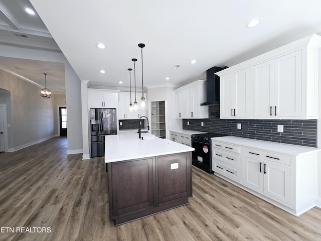 kitchen with black appliances, wall chimney exhaust hood, light countertops, and a sink