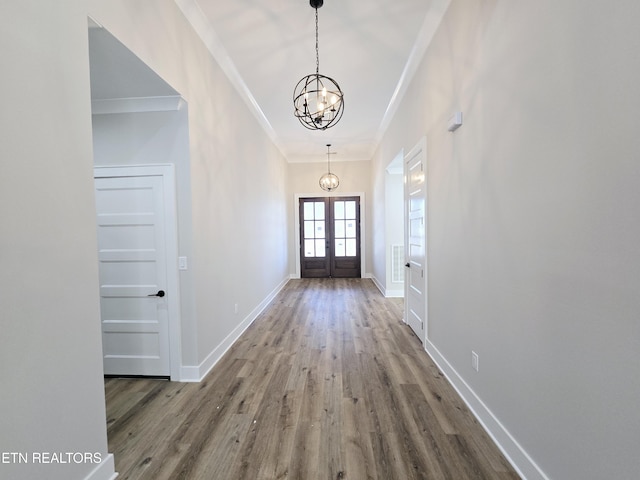 doorway featuring wood finished floors, baseboards, french doors, crown molding, and a notable chandelier