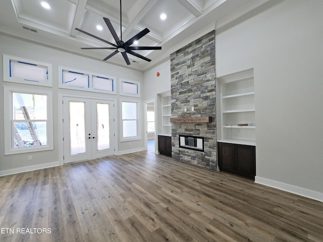 unfurnished living room featuring visible vents, baseboards, a stone fireplace, french doors, and wood finished floors