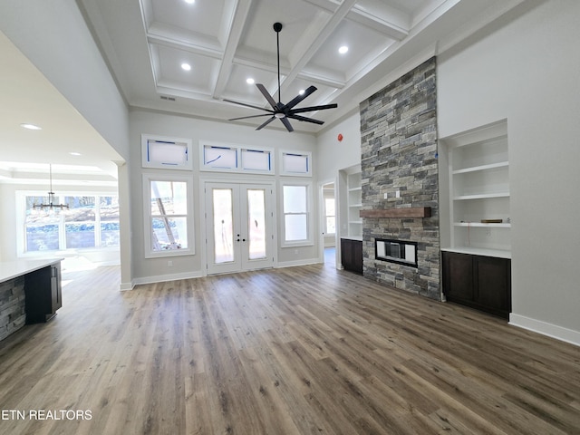 unfurnished living room featuring baseboards, a stone fireplace, and wood finished floors