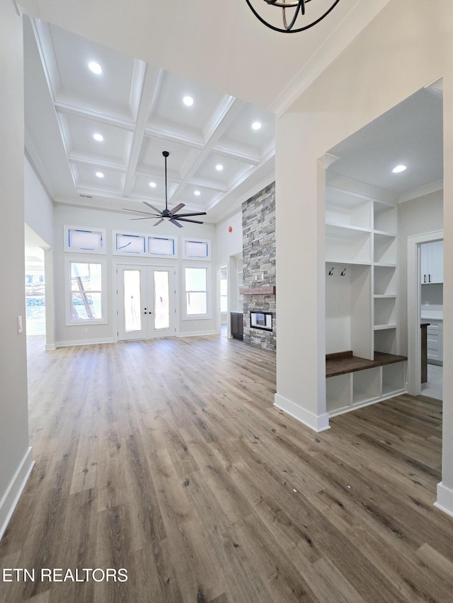 unfurnished living room featuring wood finished floors, coffered ceiling, ceiling fan, and a fireplace