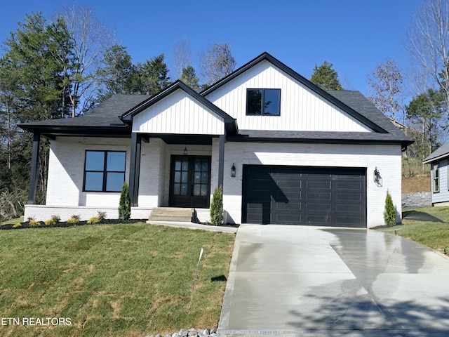 modern farmhouse style home with a front yard, driveway, an attached garage, french doors, and brick siding