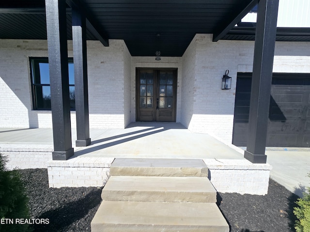 entrance to property featuring brick siding and covered porch