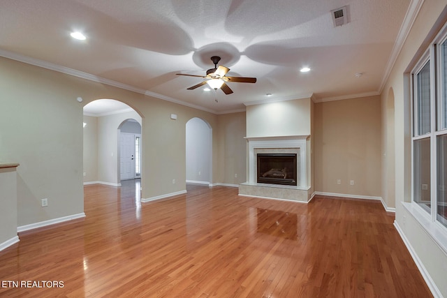 unfurnished living room with ceiling fan, light hardwood / wood-style flooring, crown molding, and a tile fireplace