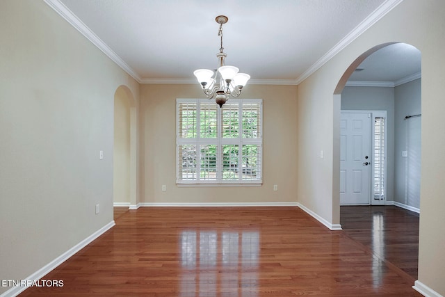 spare room featuring an inviting chandelier, dark hardwood / wood-style floors, and crown molding