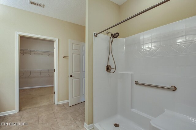 bathroom with tile patterned flooring, a textured ceiling, and walk in shower