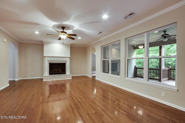 unfurnished living room featuring ornamental molding, light wood-type flooring, a premium fireplace, and ceiling fan