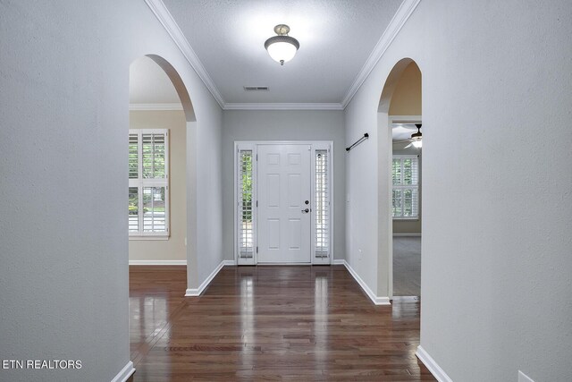 foyer entrance with a textured ceiling, ornamental molding, ceiling fan, and dark wood-type flooring