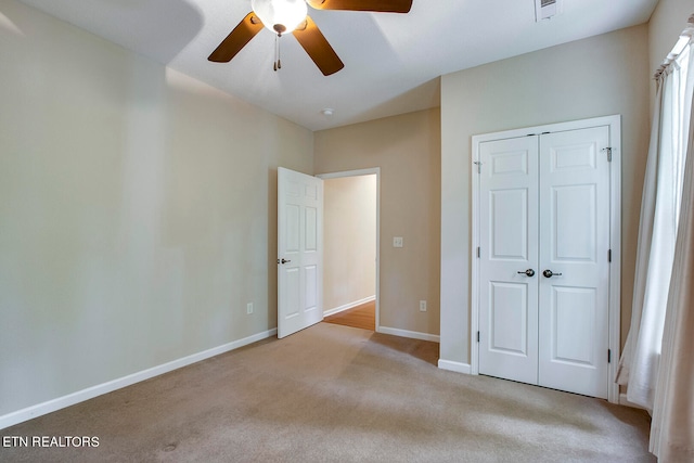 unfurnished bedroom with light carpet, ceiling fan, and a closet