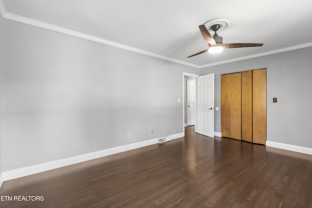 unfurnished bedroom with ceiling fan, a closet, crown molding, and dark wood-type flooring