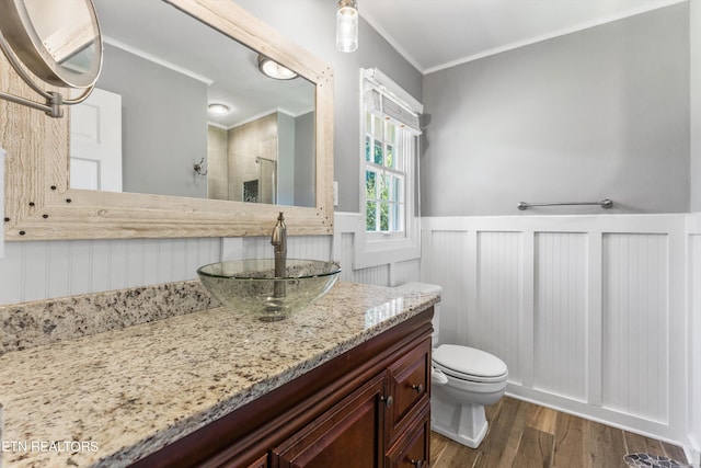 bathroom featuring a shower with shower door, vanity, crown molding, toilet, and hardwood / wood-style floors