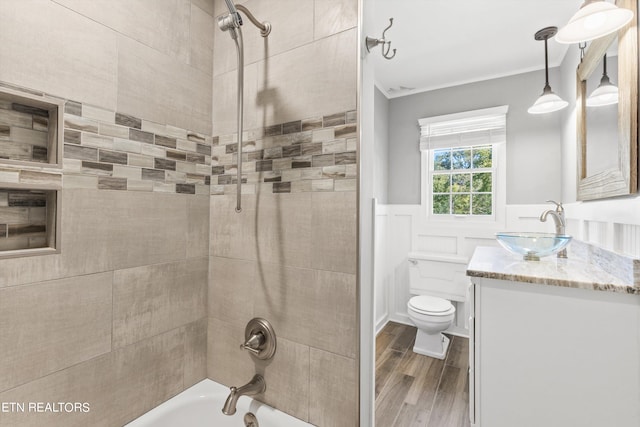 full bathroom with vanity, tiled shower / bath combo, hardwood / wood-style flooring, crown molding, and toilet