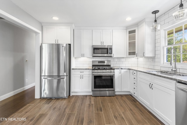 kitchen with pendant lighting, sink, dark wood-type flooring, white cabinetry, and stainless steel appliances