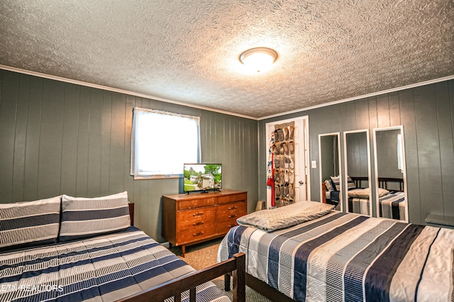 bedroom featuring a textured ceiling, wood walls, and crown molding