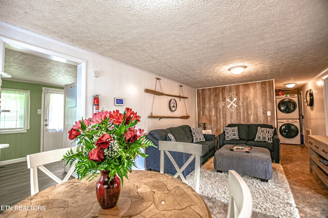 dining area featuring a textured ceiling, wooden walls, and stacked washer and dryer