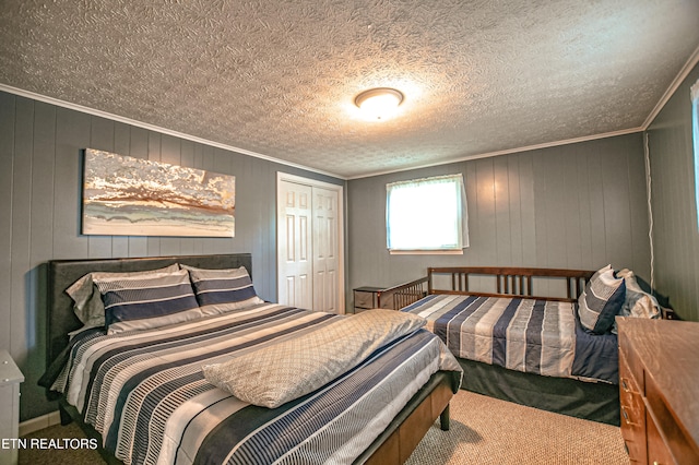 bedroom with carpet flooring, a textured ceiling, wooden walls, a closet, and crown molding