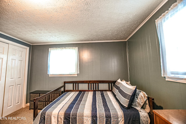 bedroom with crown molding, carpet flooring, wood walls, and a closet