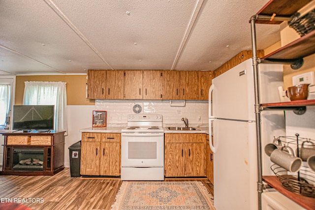 kitchen featuring sink, white appliances, a textured ceiling, light hardwood / wood-style flooring, and decorative backsplash