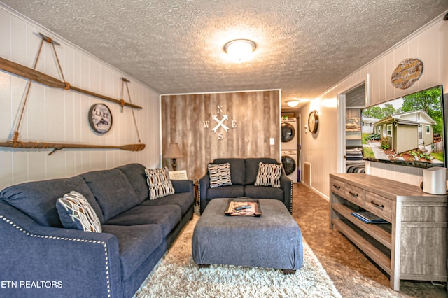 carpeted living room featuring a textured ceiling, stacked washing maching and dryer, and wooden walls