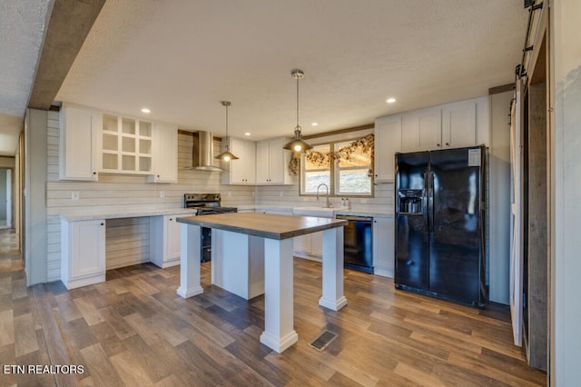 kitchen featuring white cabinetry, wall chimney range hood, dark hardwood / wood-style flooring, and black appliances