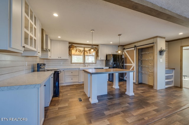 kitchen featuring white cabinetry, range with electric stovetop, a barn door, and black fridge