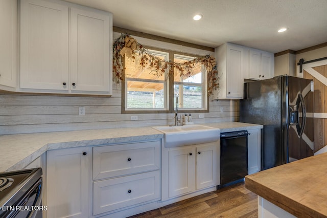 kitchen featuring sink, white cabinets, hardwood / wood-style flooring, a barn door, and black appliances