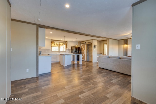 unfurnished living room with a barn door, hardwood / wood-style floors, and ceiling fan