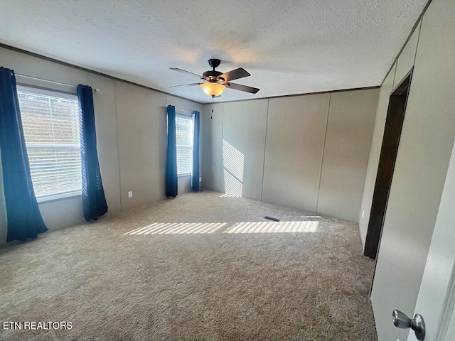 unfurnished room with light colored carpet, a healthy amount of sunlight, and a textured ceiling