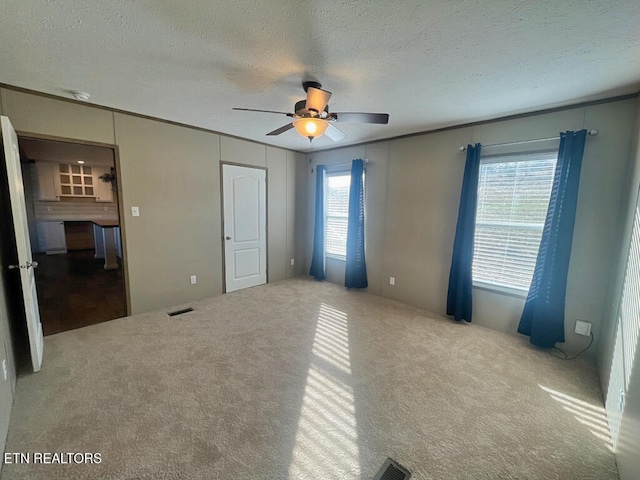 unfurnished bedroom featuring multiple windows, light colored carpet, and ceiling fan