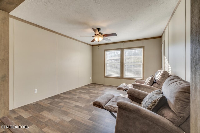 living room featuring ceiling fan, hardwood / wood-style flooring, ornamental molding, and a textured ceiling