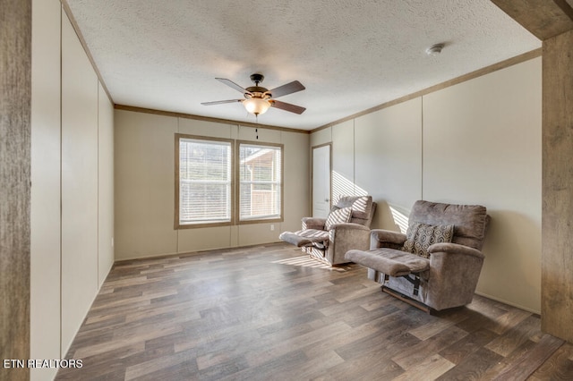 sitting room with crown molding, ceiling fan, dark hardwood / wood-style floors, and a textured ceiling