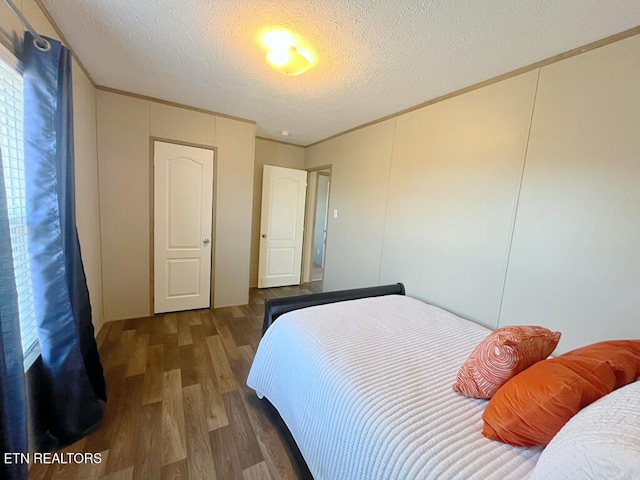 bedroom with crown molding, a textured ceiling, and dark hardwood / wood-style flooring