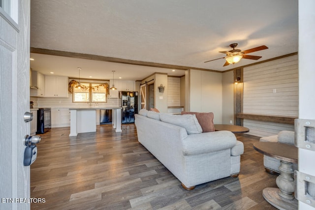 living area with dark wood-style floors, recessed lighting, ceiling fan, and ornamental molding